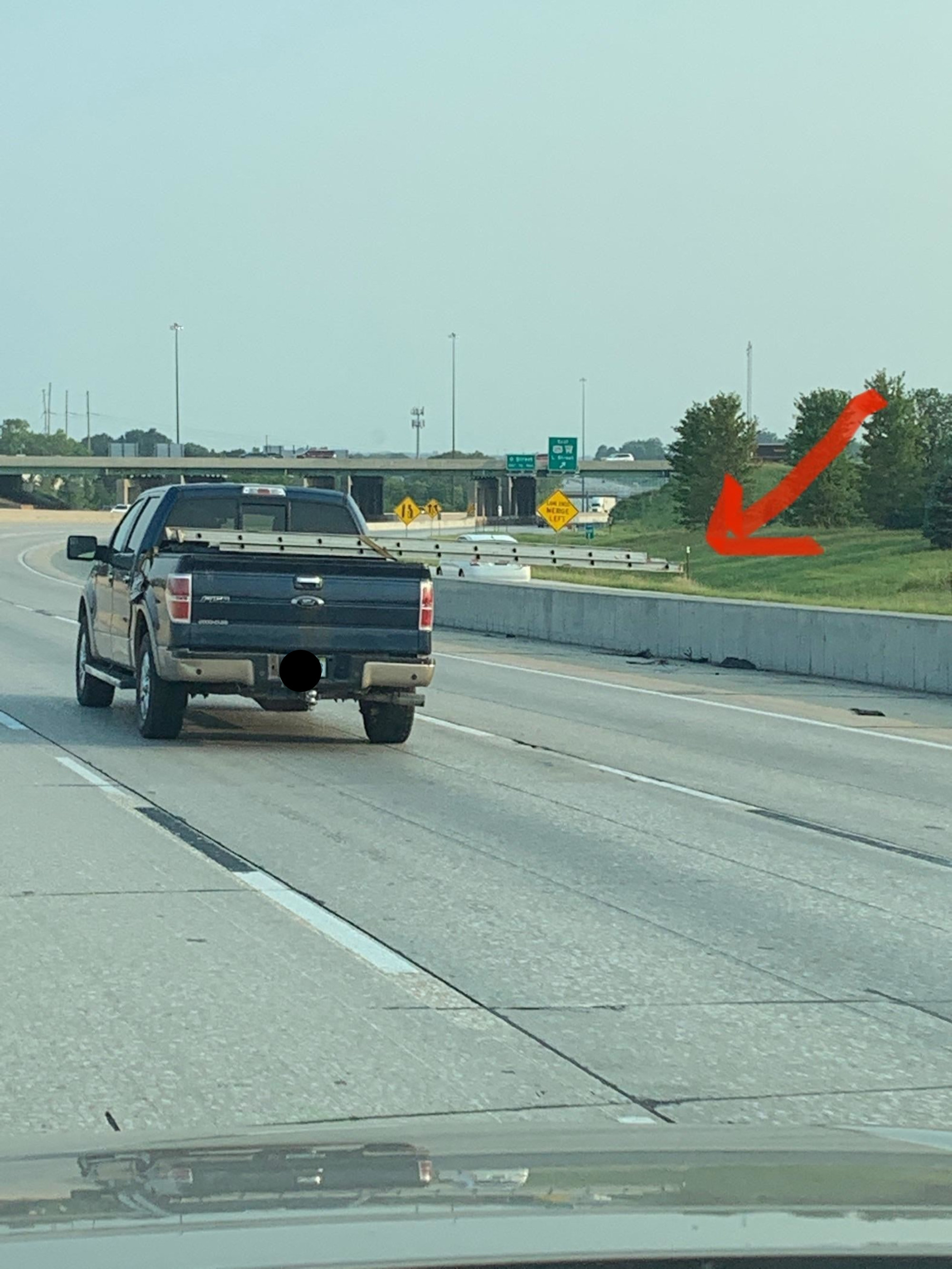 Pickup truck with a ladder in the back that extends across another highway lane