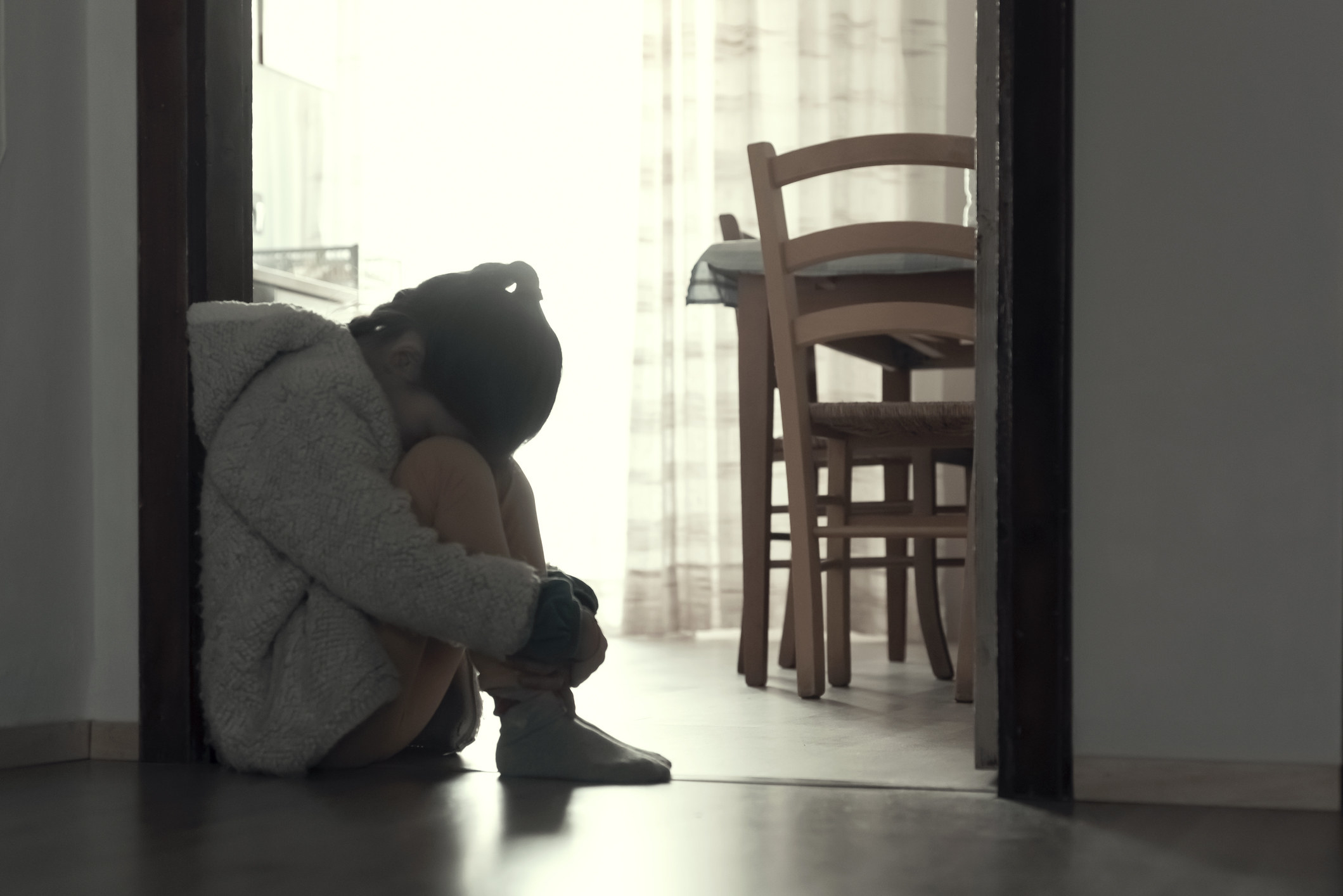 A young girl sits alone with her head down