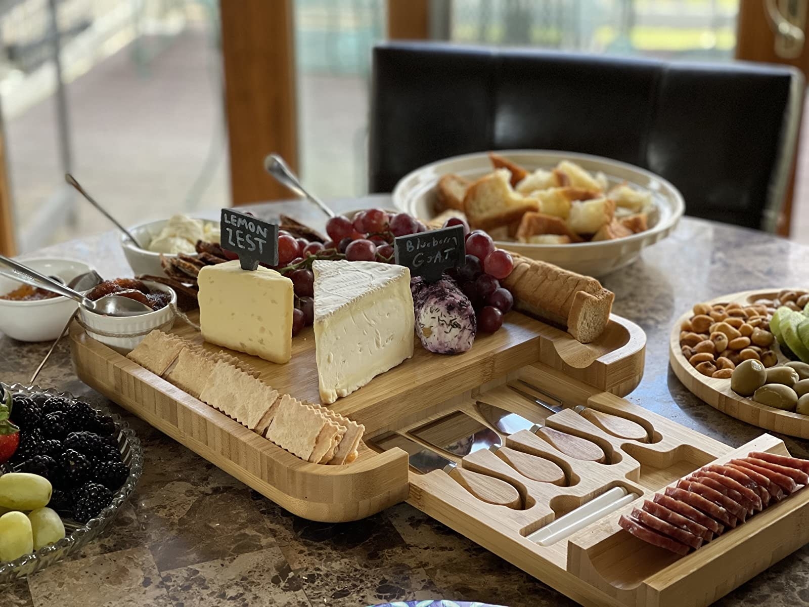 A reviewer shows the charcuterie set filled with various cheeses, fruit, crackers, and spreads.