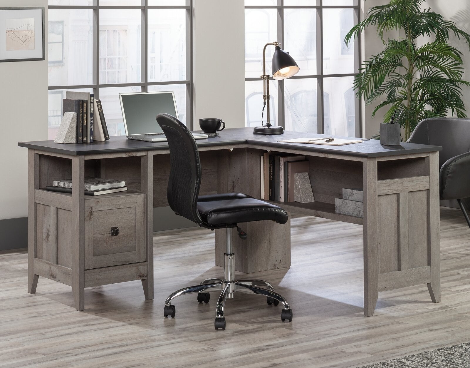 A dark gray and black L-shaped desk with interior shelf and drawer