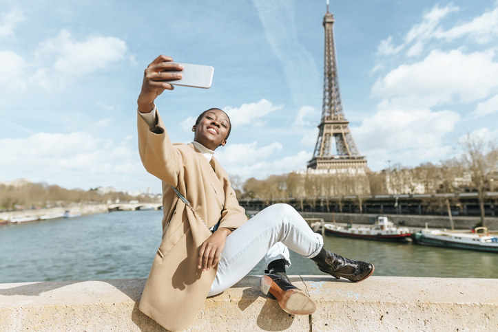 Young person taking a selfie in front of the Eiffel Tower