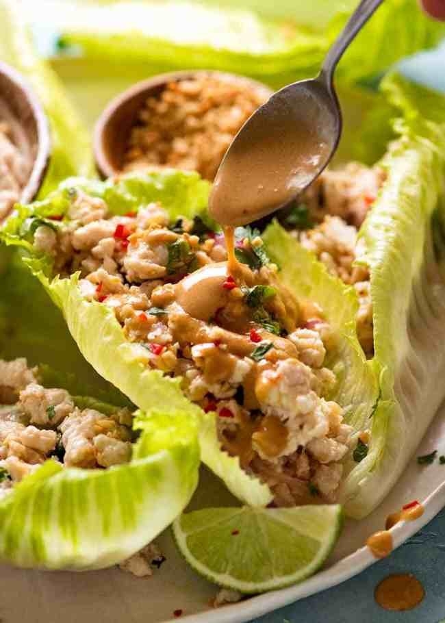Drizzling sauce over Larb Gai in a lettuce wrap