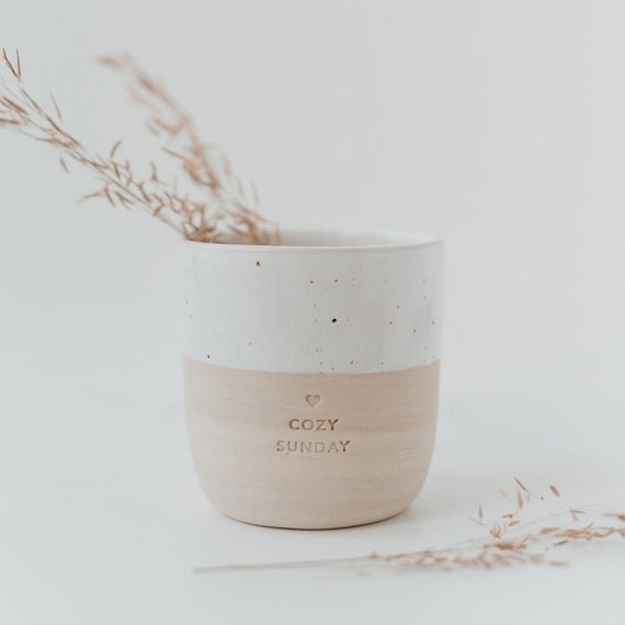 a white and tan mug with a heart and the words "cozy Sunday" engraved in the mug