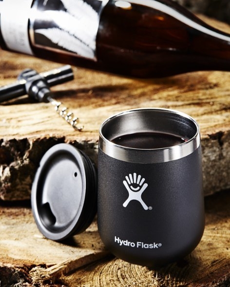 a stainless steel wine glass tumbler with lid and wine bottle opener in the background.