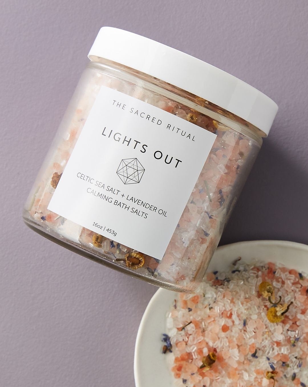 jar of the sacred ritual lights out bath salts, next to a dish of pink and white salts