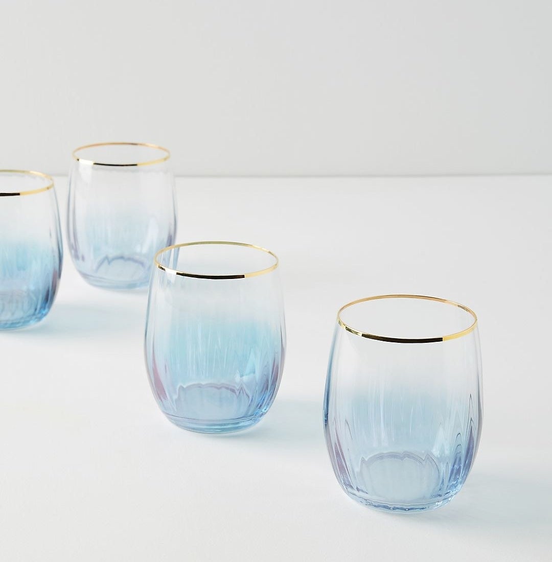 four blue/purple stemless wine glasses with a gold rim