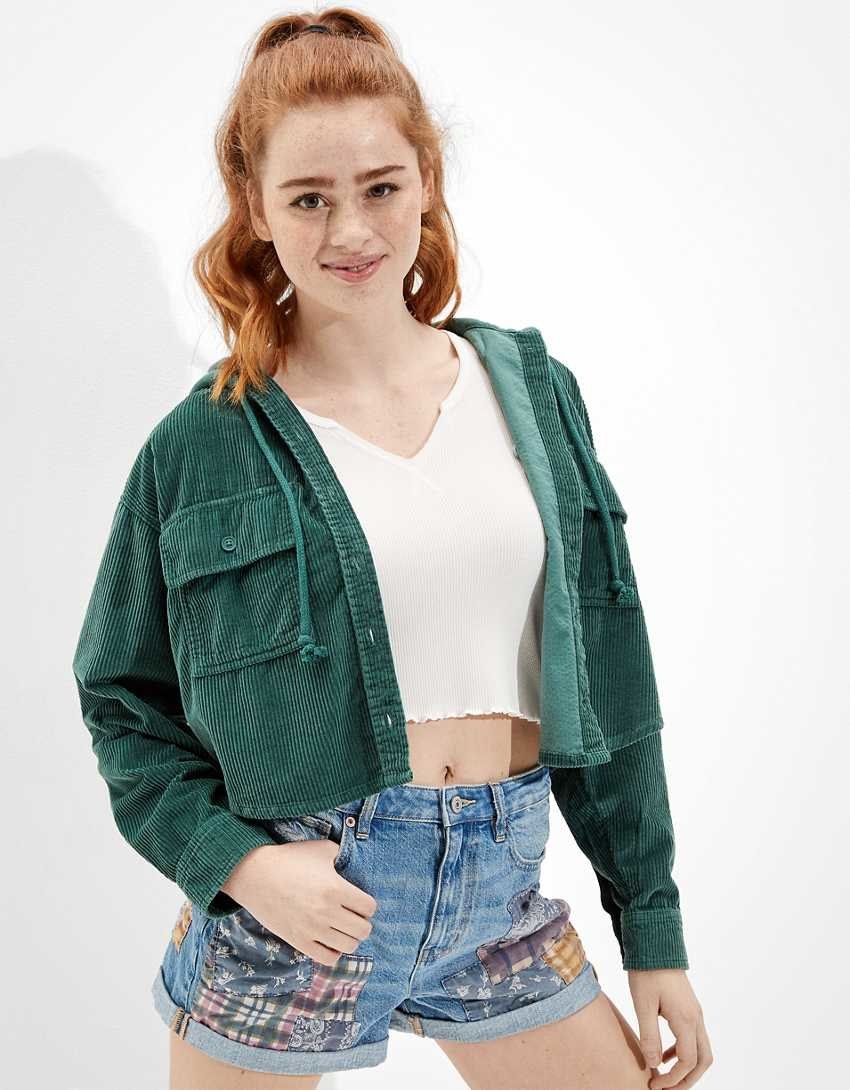 A model wearing the emerald green corduroy cropped top over a tank