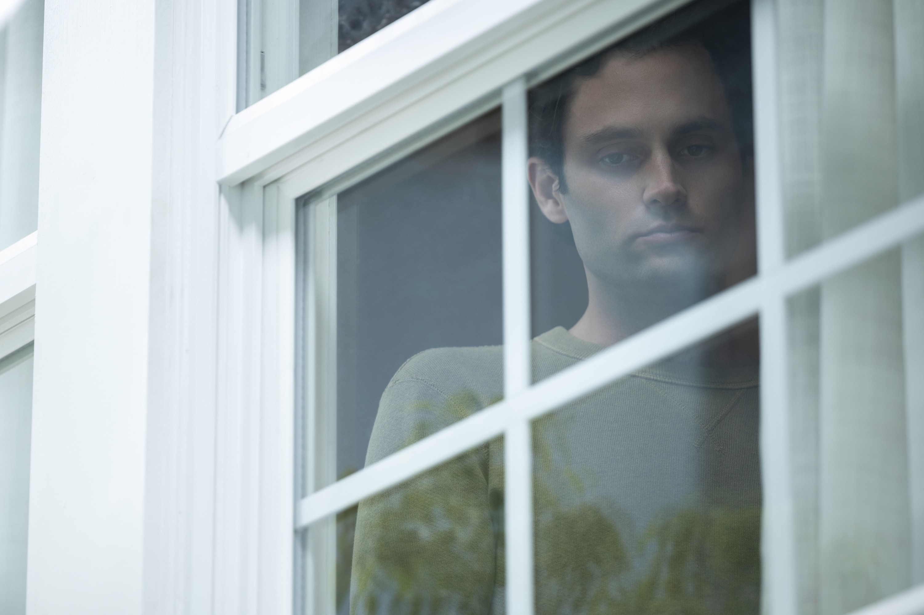 Penn Badgley looking down from a second floor window