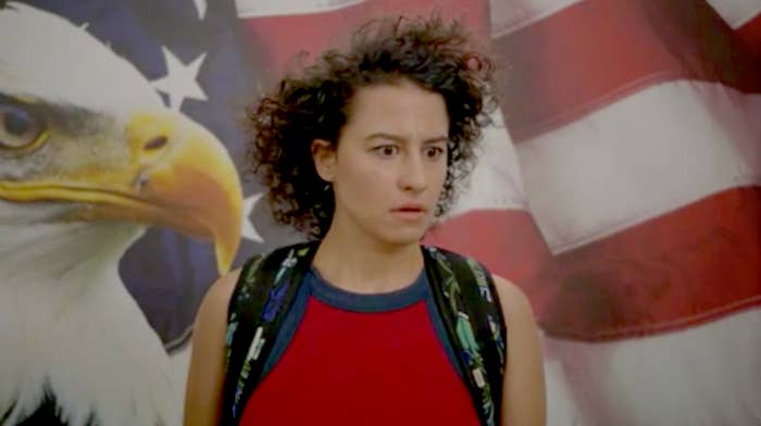 Ilana Glazer looking shocked in front of an American flag