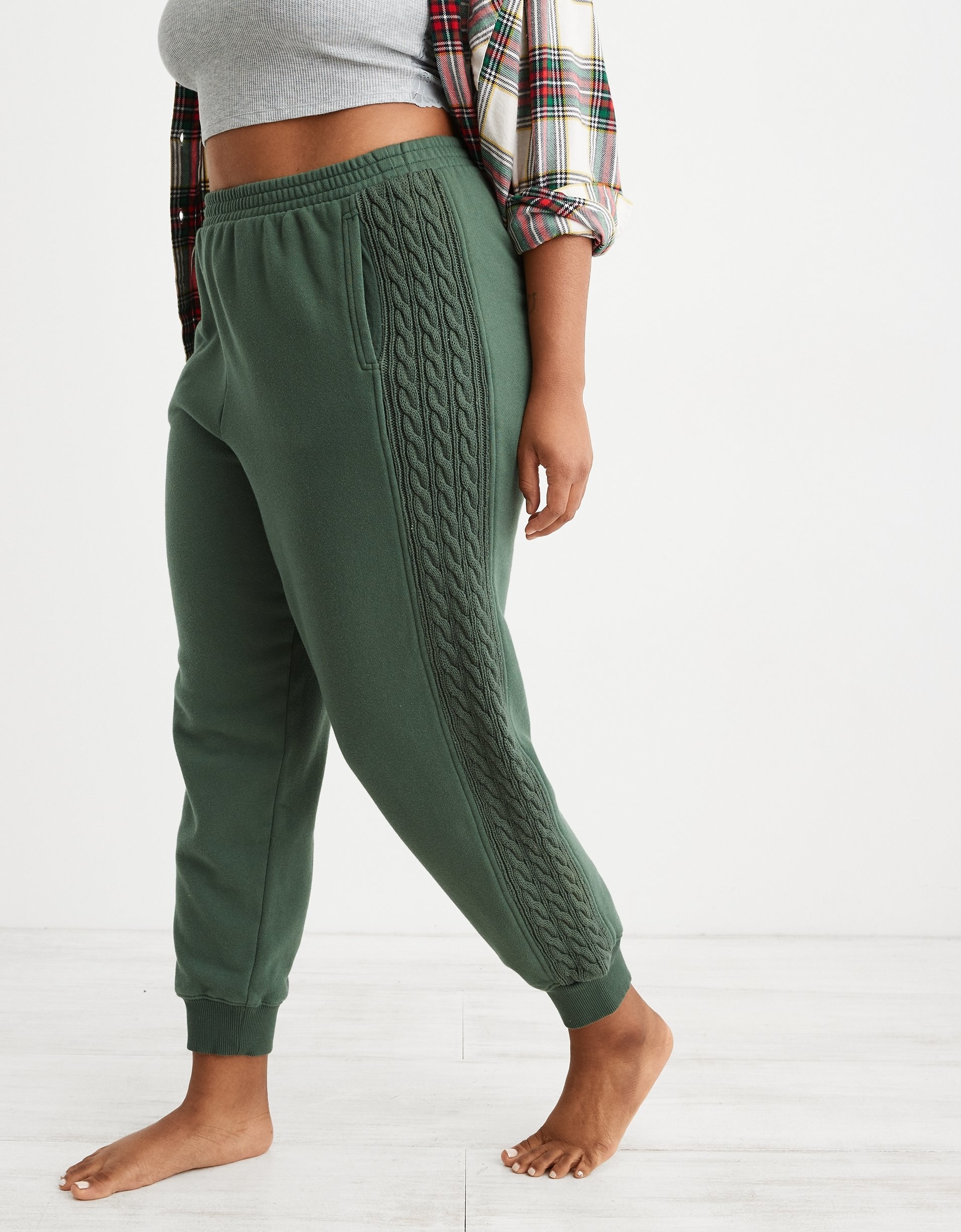 model in green joggers with knit panels down the sides of both legs