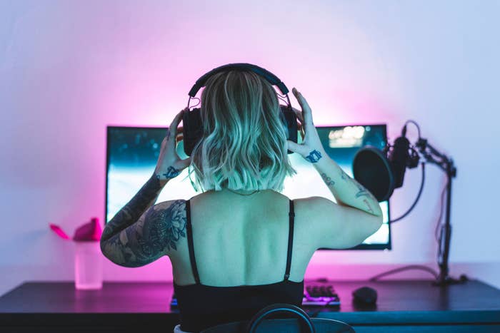 Woman putting on headphones in front of desktop computer