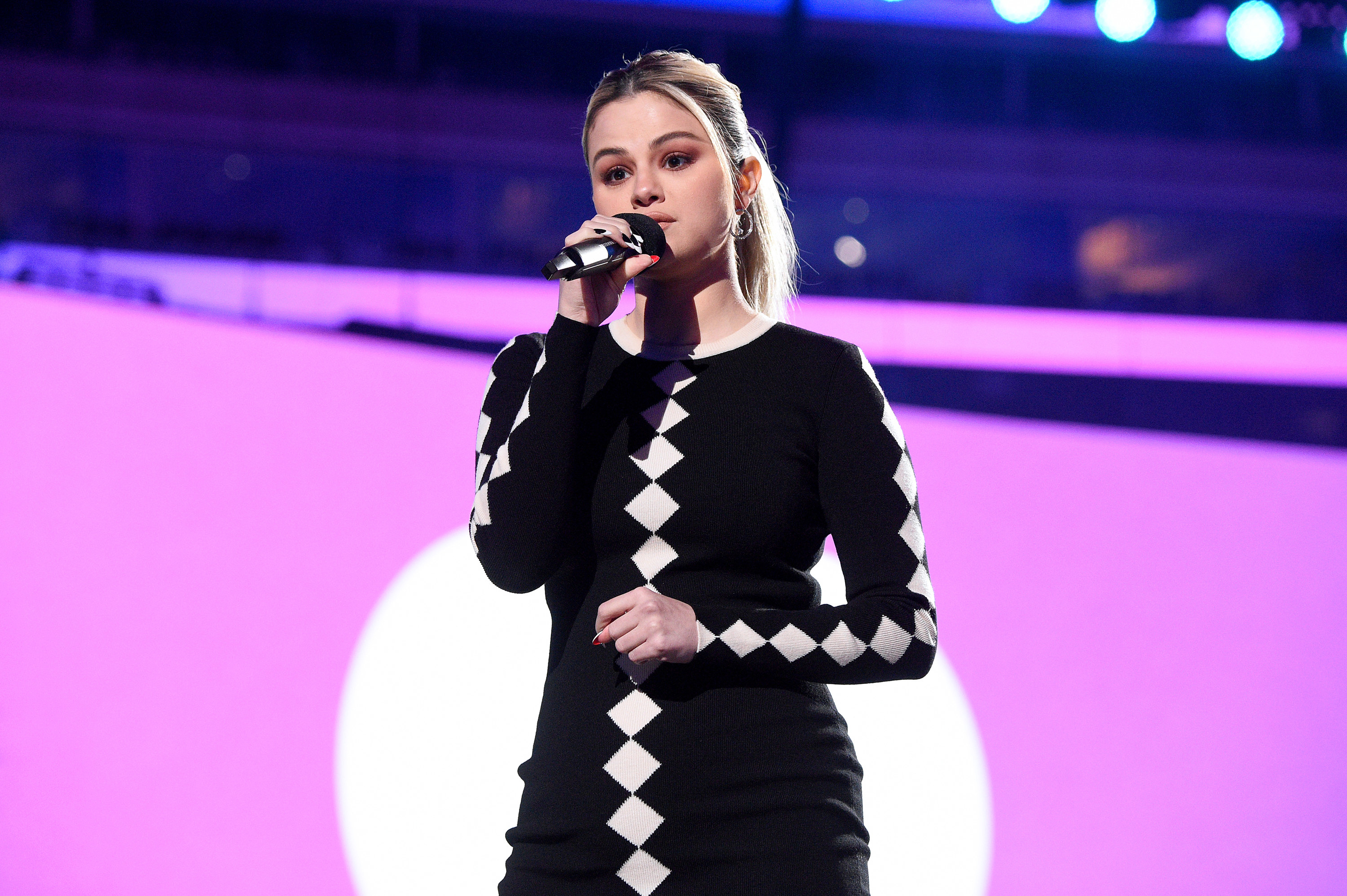 Selena standing onstage with a microphone