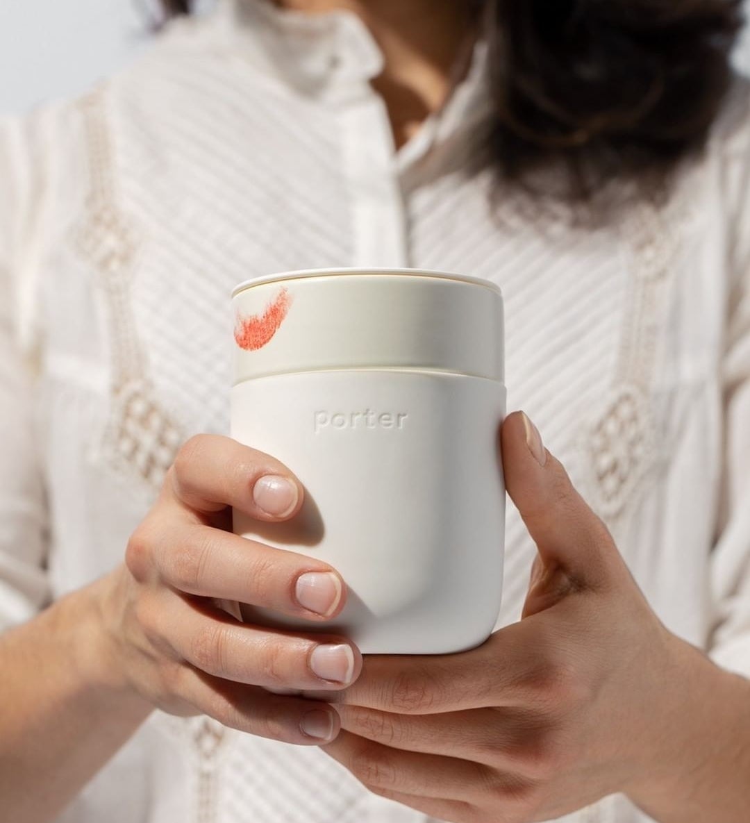 someone holding up the reusable ceramic tumbler with a lipstick mark around the rim