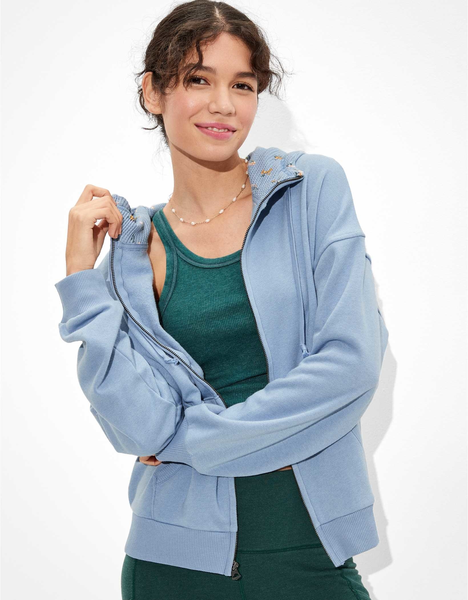 Model wearing the light blue zip-up over green tank with sweats
