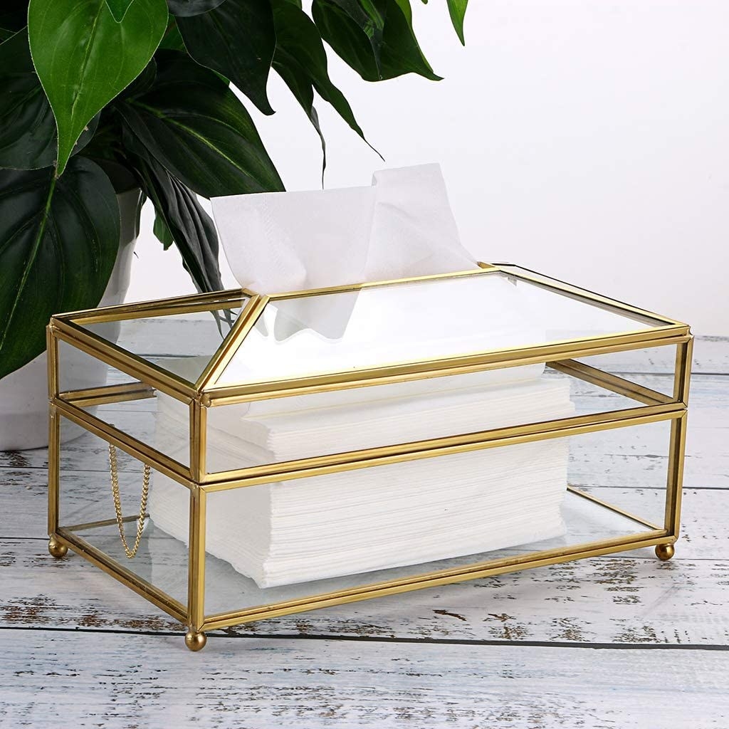 A clear glass decorative box for storing tissues, with a metal gold-colored frame