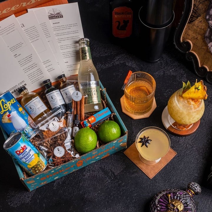 a top-down view of an open box filled with drink ingredients next to three cocktails
