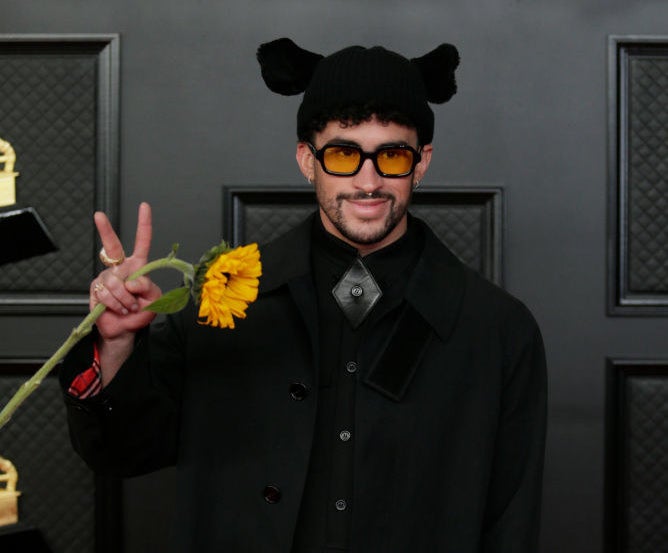 Bad Bunny holding a daisy and giving the peace sign on the Grammys red carpet