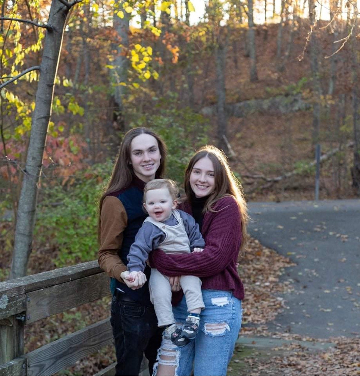 The happy family smiling while standing on a scenic bridge