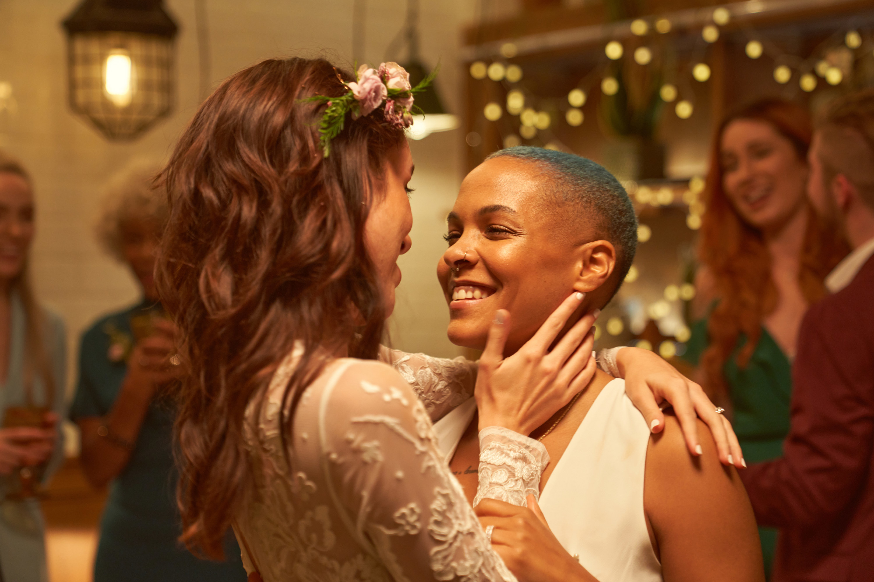 Two lesbians on their wedding day smiling and staring at each other with awe.