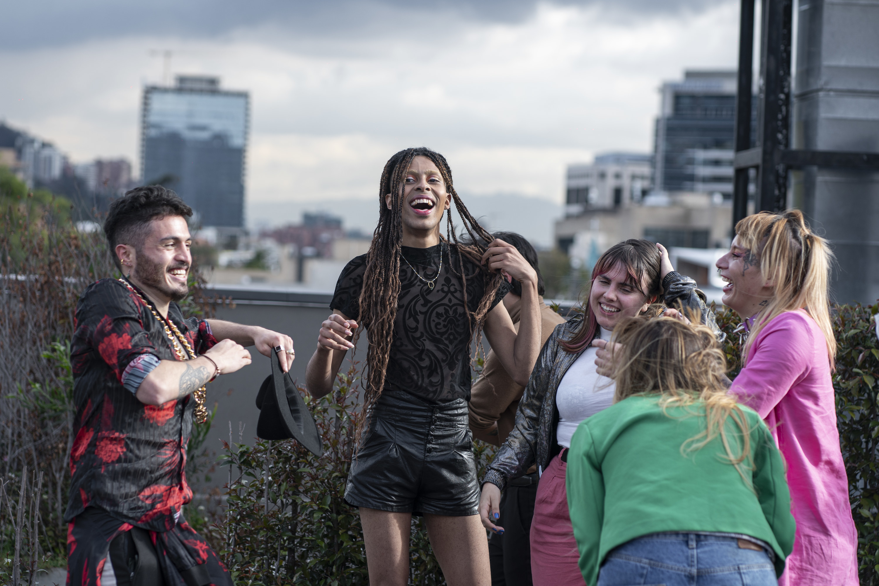 A group of 6 people laughing on the rooftop of a city building.