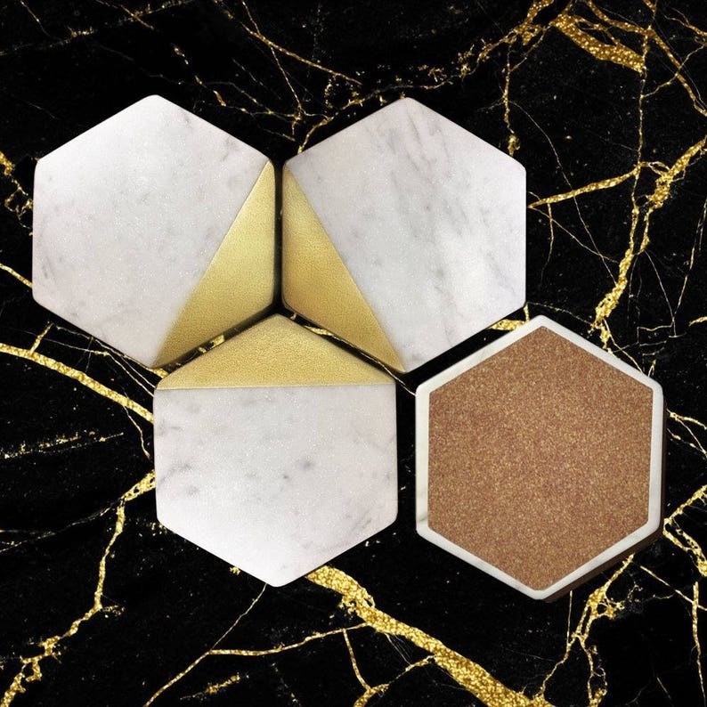 Four marble coasters with gold accents and a cork backing