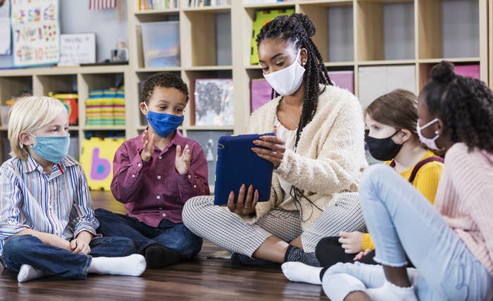 Teacher with students, all wearing masks