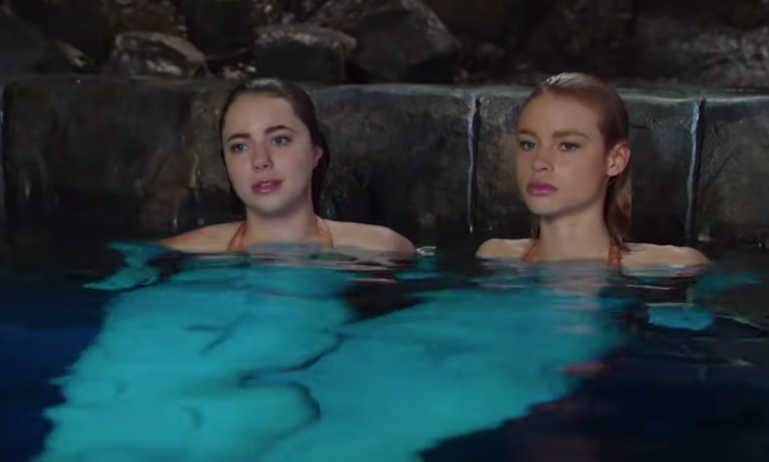 Two mermaids sit in the water together