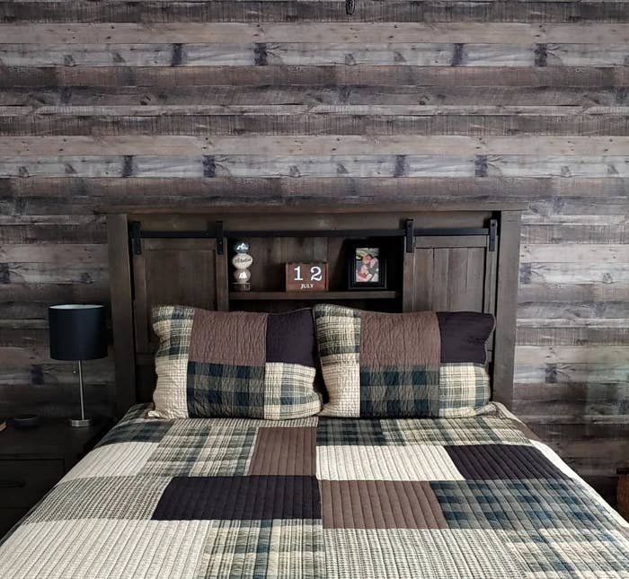 Reviewer image of dark brown wood wallpaper behind bed