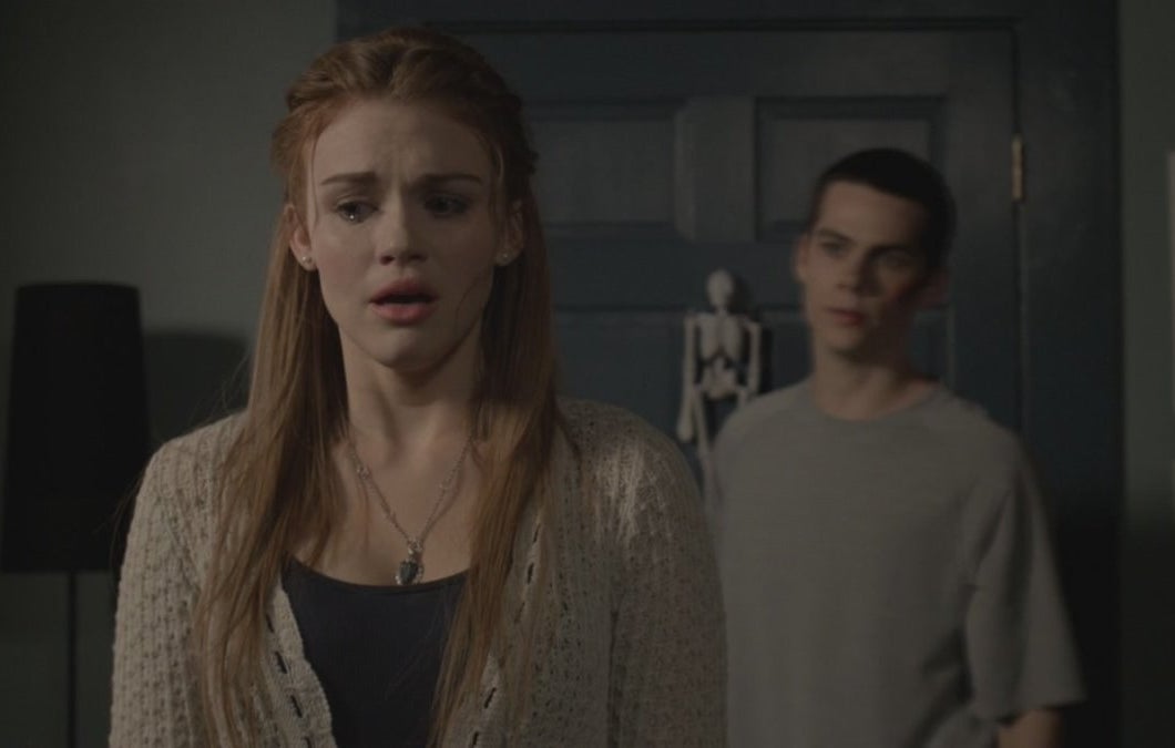Lydia from "Teen Wolf" cries and looks afraid, with Stiles watching from the background