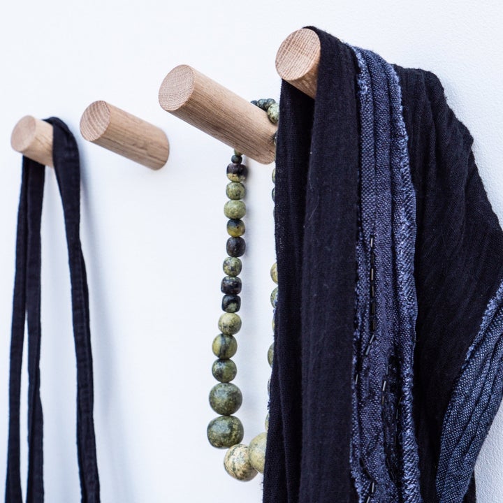 four wooden hooks with a bag, scarf, and necklace on three