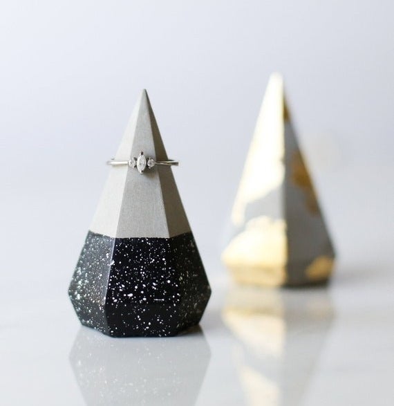 Two concrete ring holders, one with a black and white speckle base, and the other with a gold foil pattern.