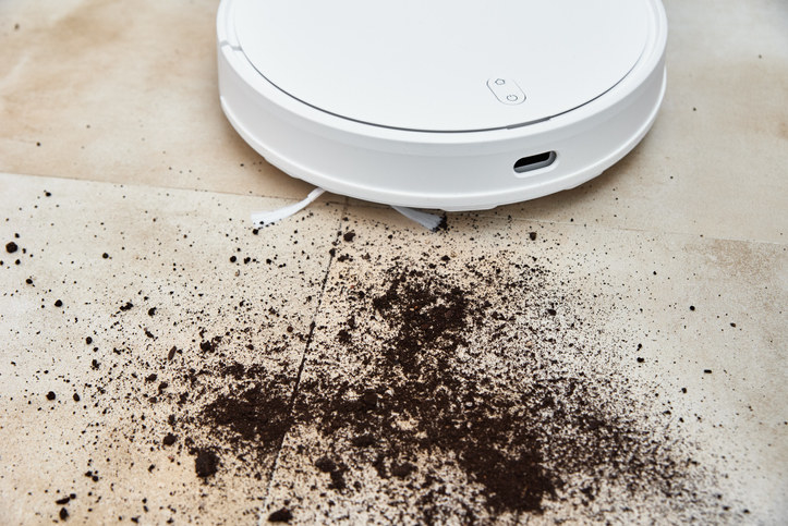 A Roomba sucking up dirt on the floor
