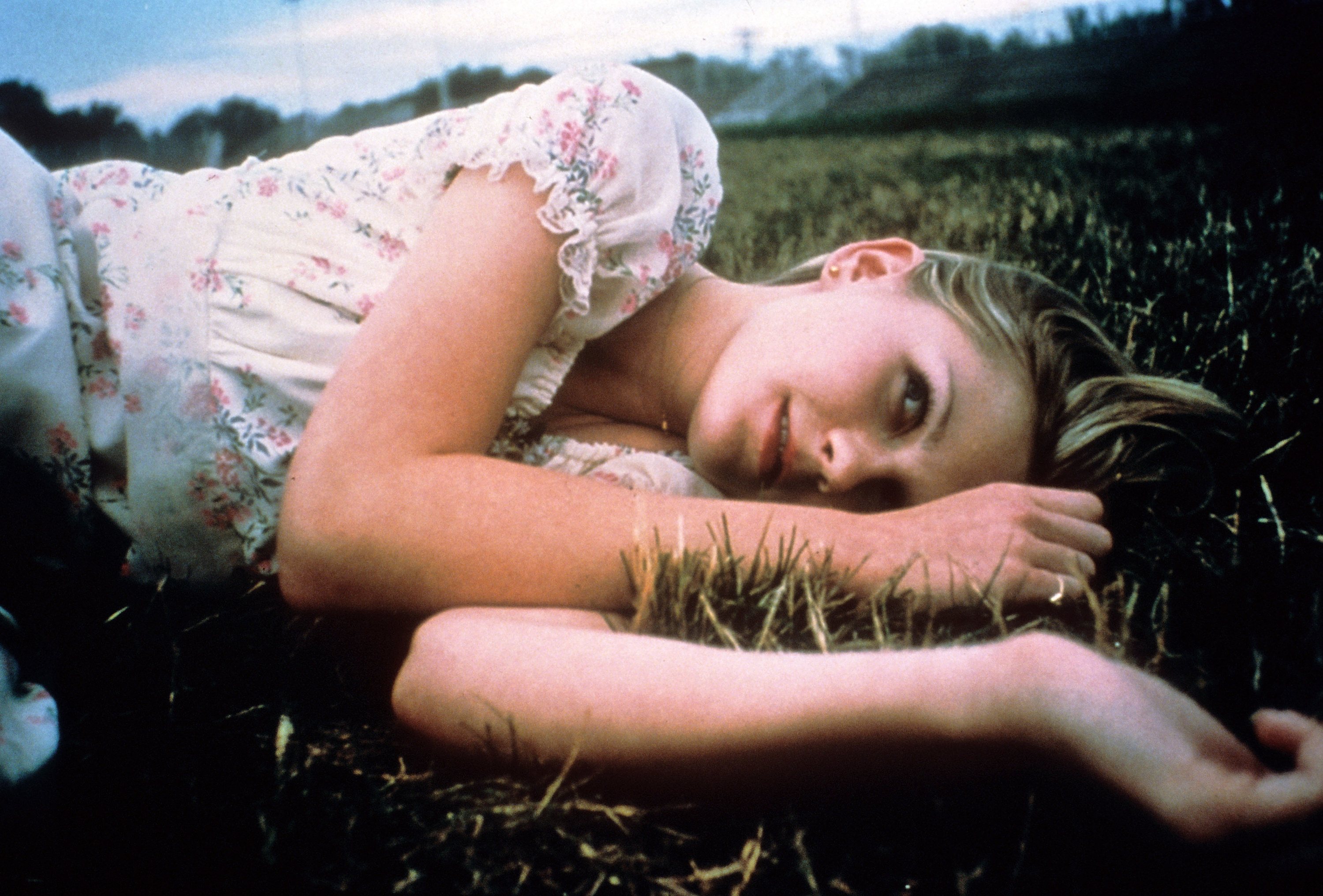 Dunst lays in the grass in a promo still for The Virgin Suicides