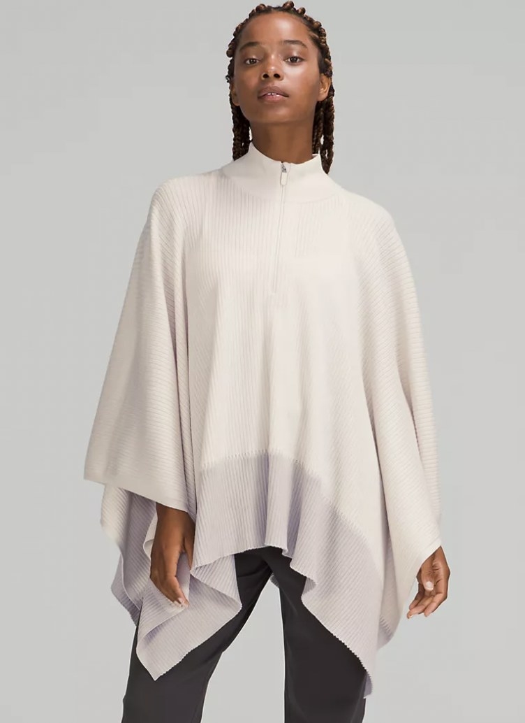 front view of model wearing the poncho in white with a grey striped hem, and a half zipper at the neck