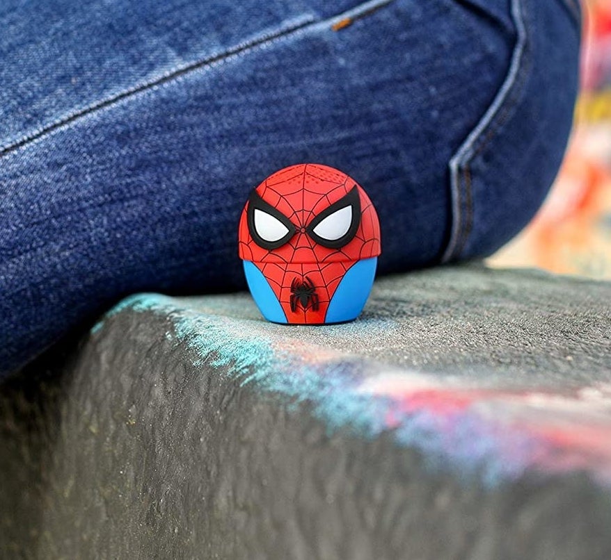 A small round speaker that looks like spider man in his suit, about 2 inches tall