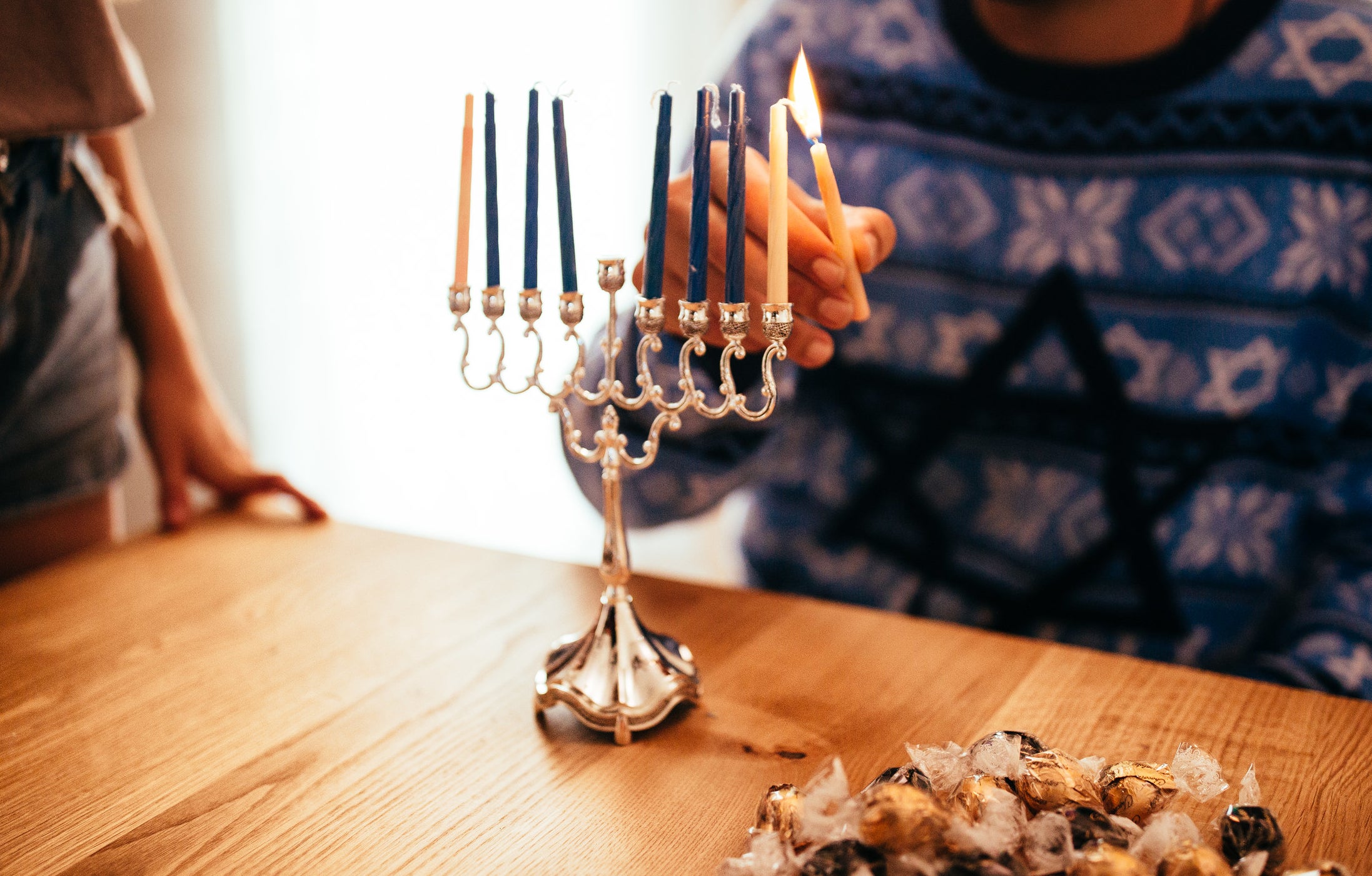 man lighting the first candle for hanukkah