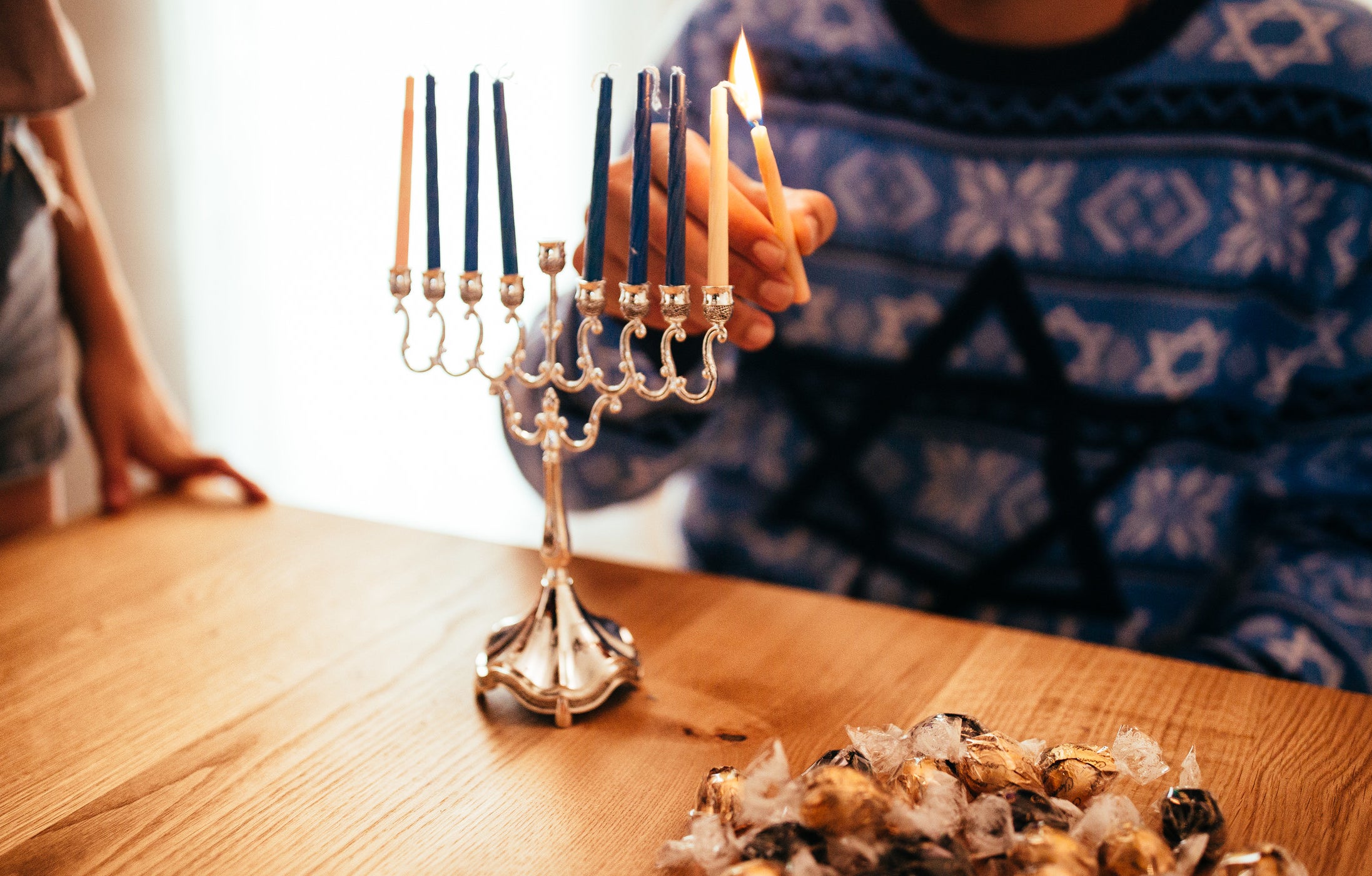 man lighting the first candle for hanukkah