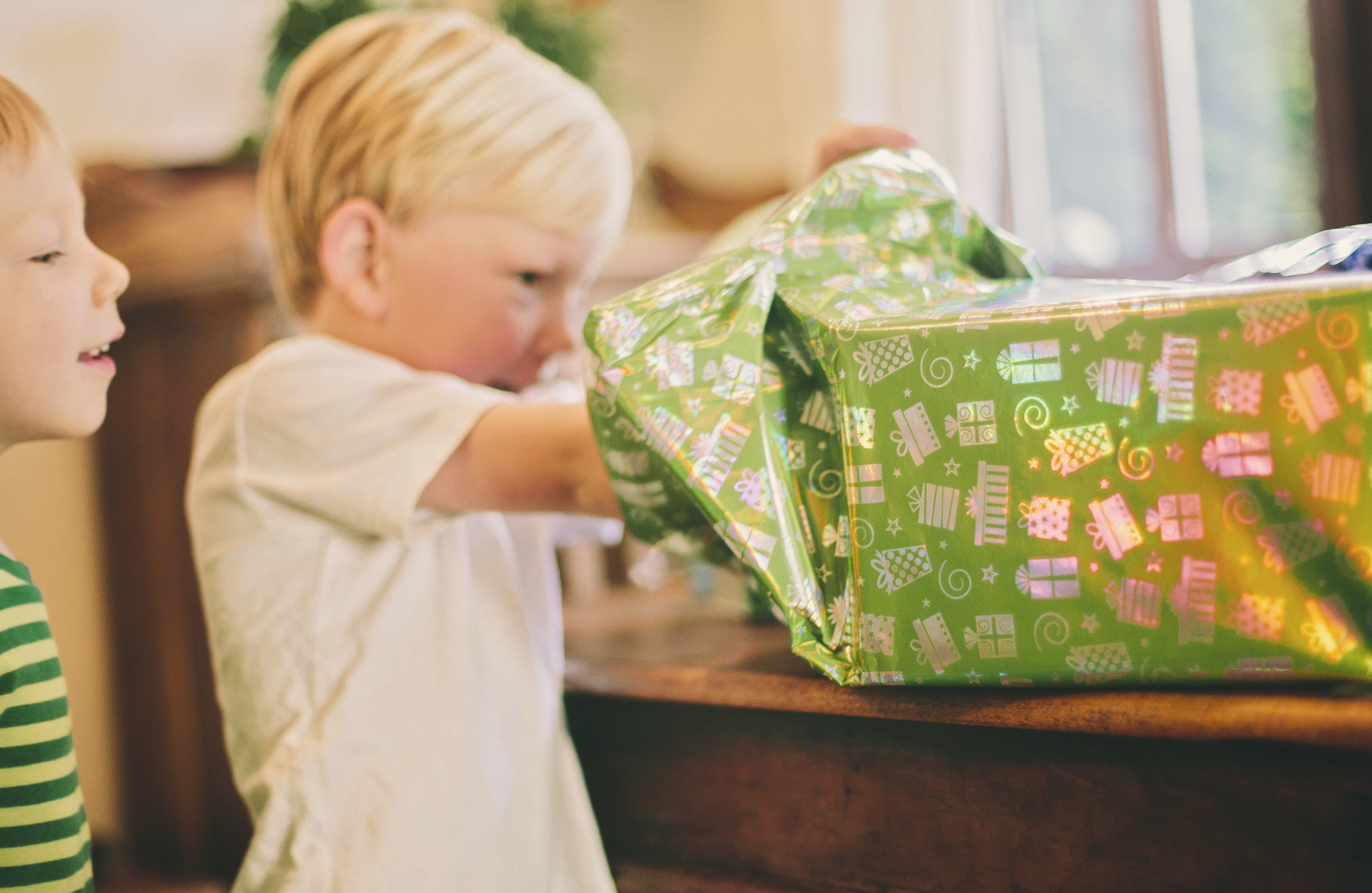 a little boy digs through a birthday box as he unwraps it