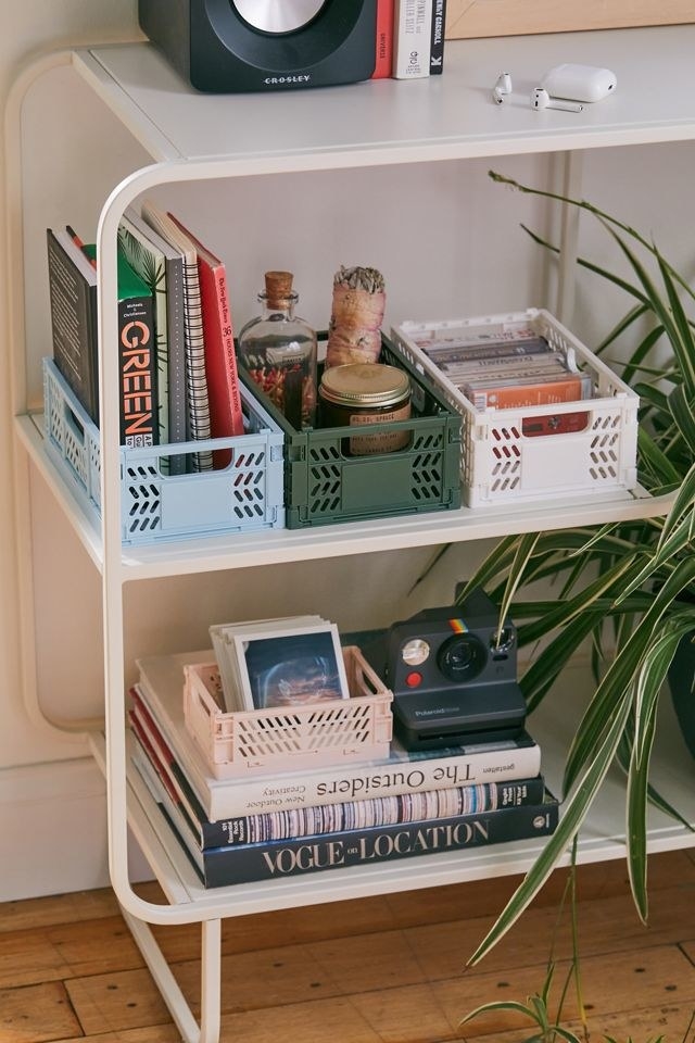 the blue, green, white, and pink organizers on a shelf. Each filled with little items like books, photos, and candles.