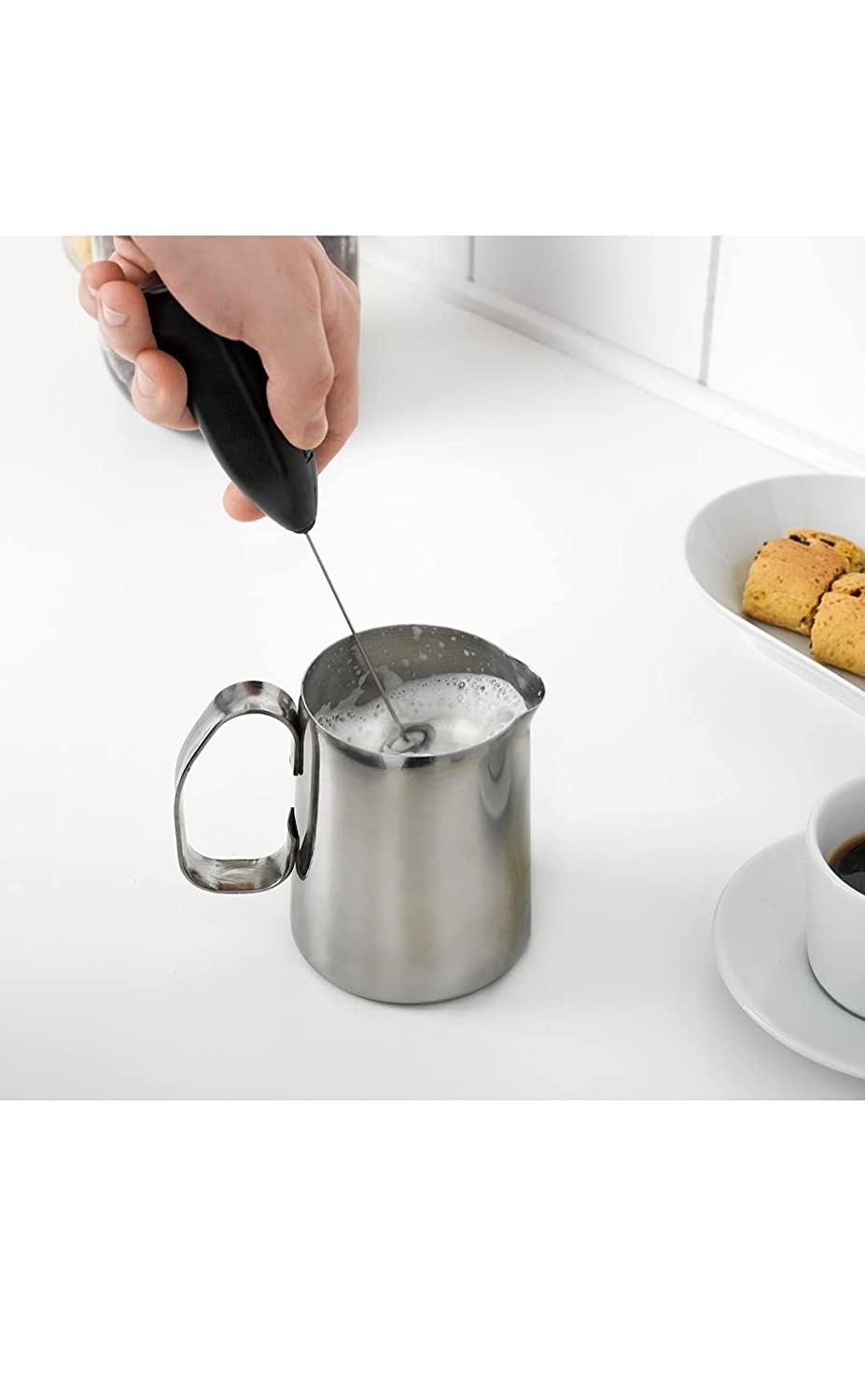 A person frothing milk in a milk frother