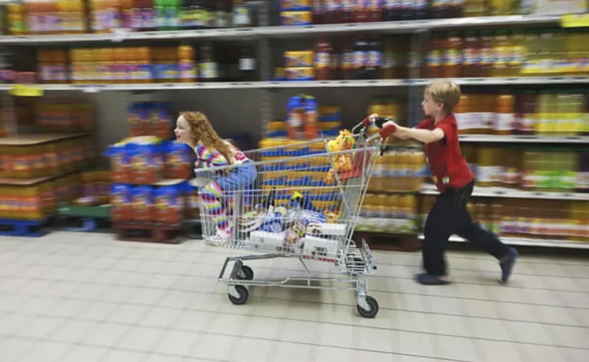 kid pushing another kid in a trolley