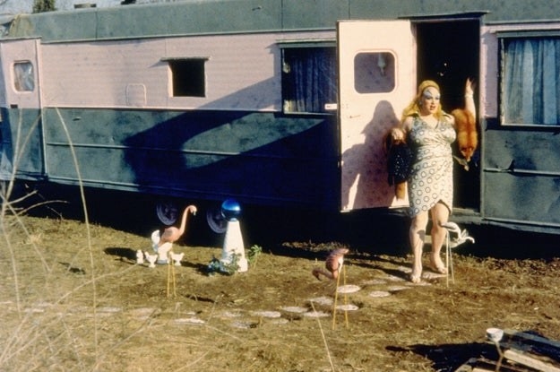 Divine stands outside her trailer in pink flamingos