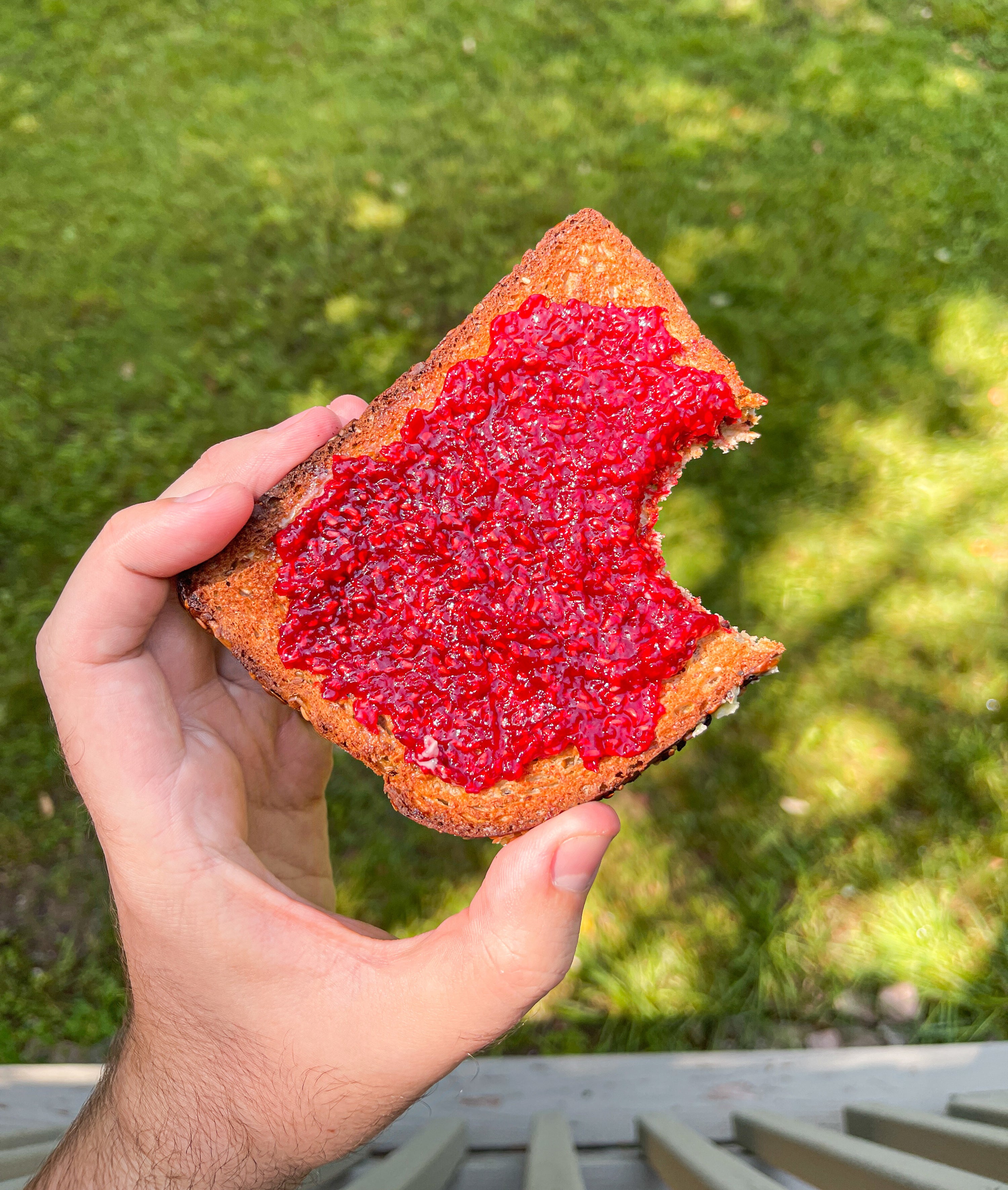 Raspberry jam spread on a bitten piece of toast