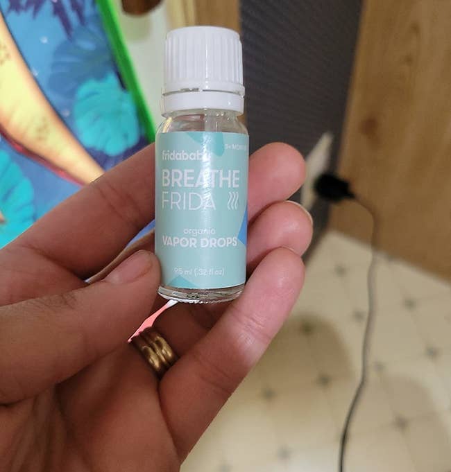 reviewer's hand holding small bottle of vapor drops