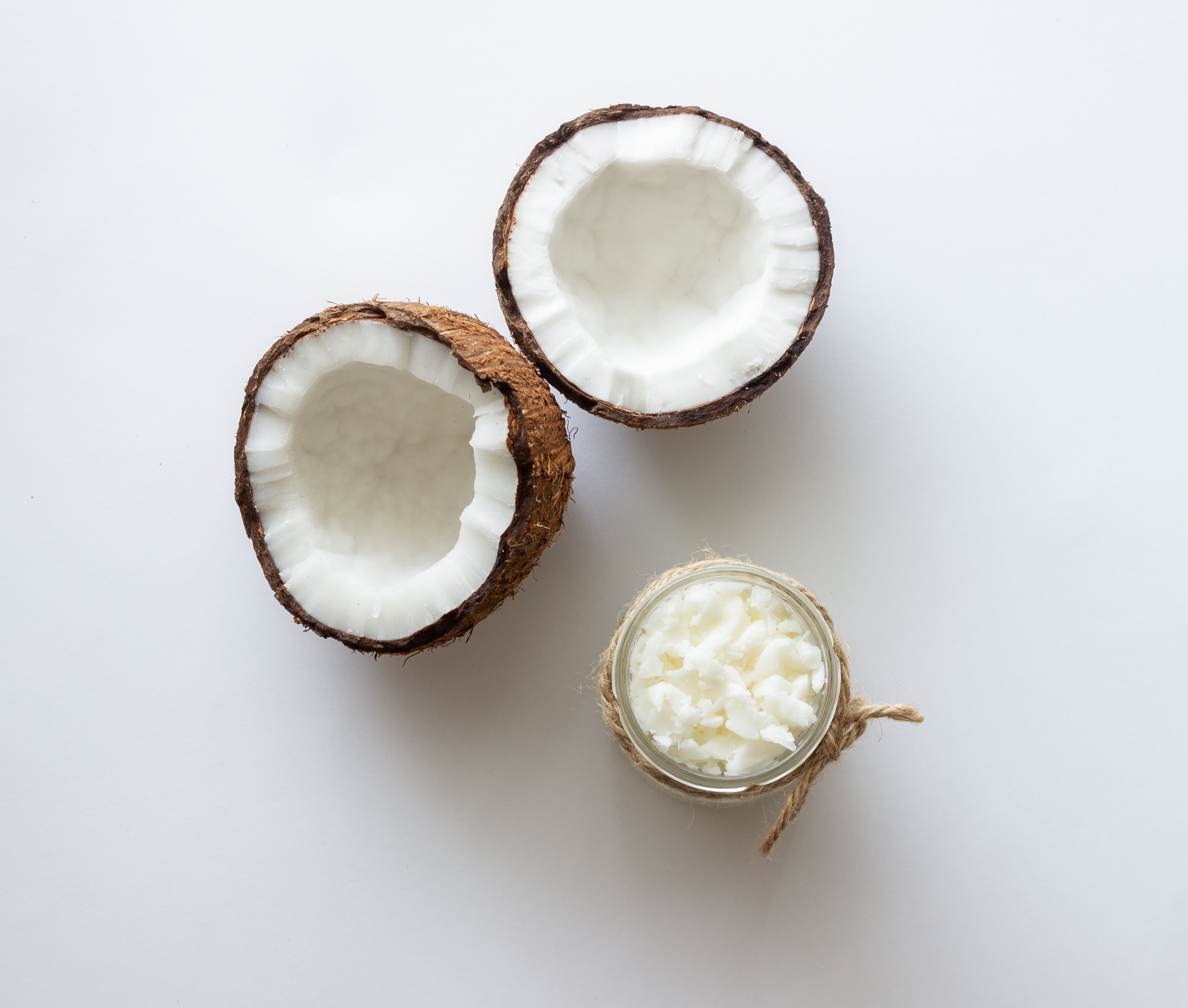 A coconut cut in half next to a jar of coconut