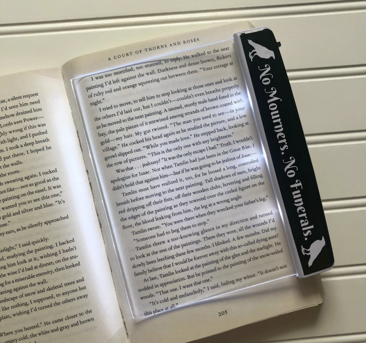 a flatlay booklight that has six of crows no mourners no funerals quote on the side