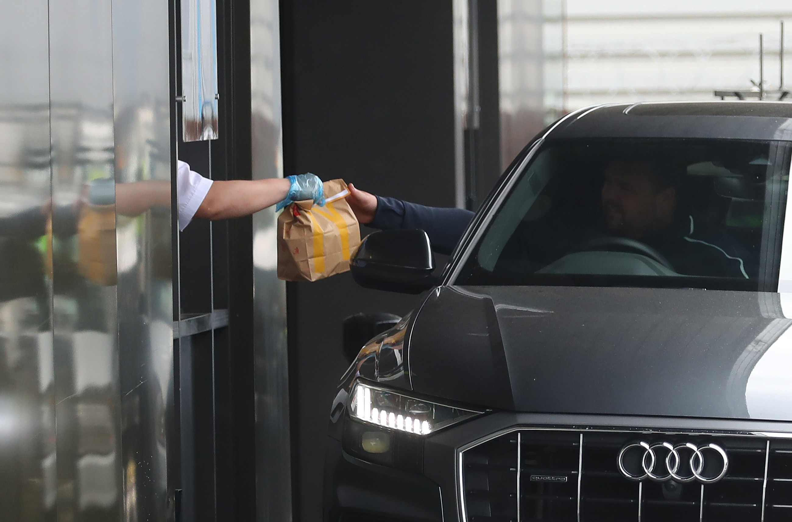 Worker handing a bag of food to a drive-thru customer
