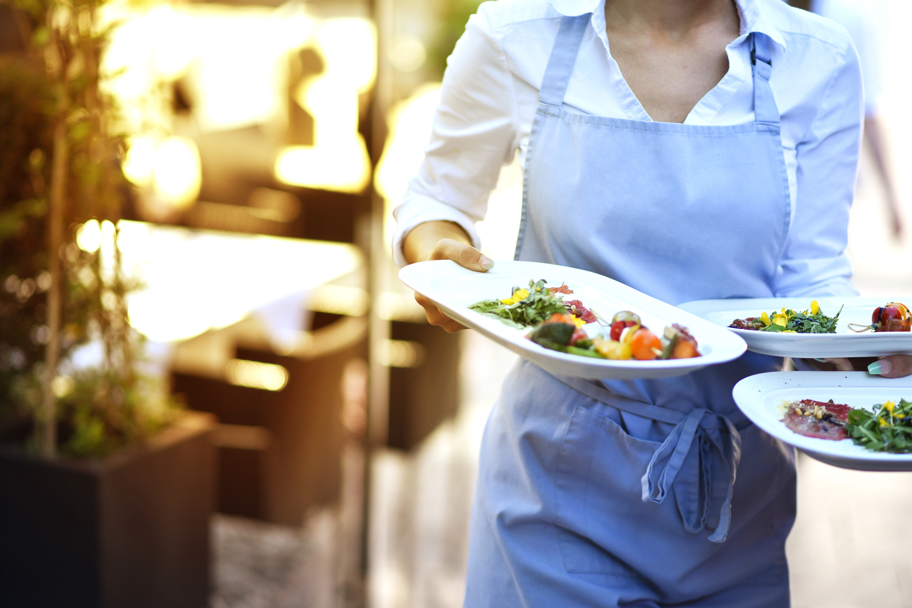 Restaurant server carrying three plates out of the kitchen