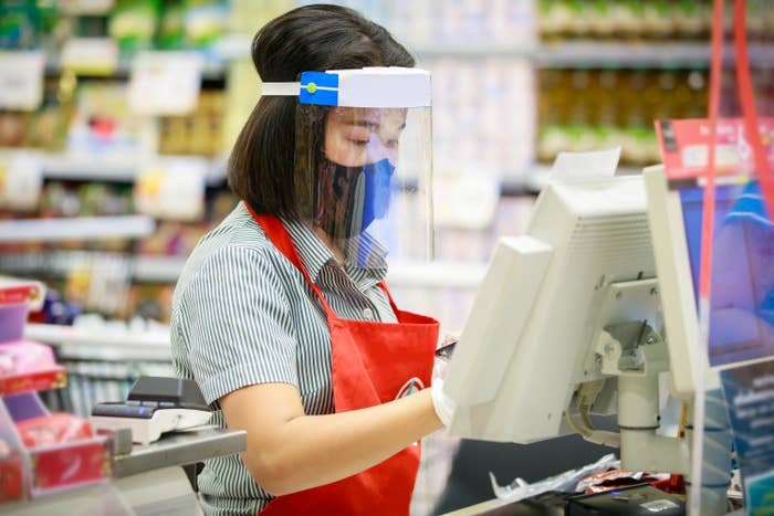 Woman wearing a mask and face shield while working as a cashier