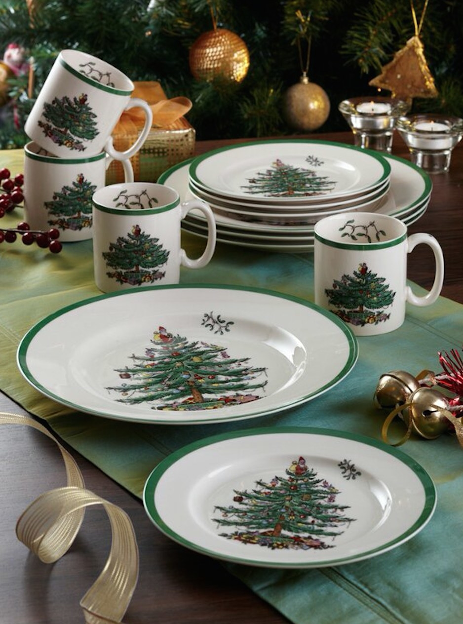 White dinnerware with christmas tree on it and green border, bowl, small plate, stacked plates, and mugs